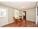 Cozy dining room with wood floors, a wooden table with chairs, and bright, floral wallpaper at 1004 Midwood Dr, Monroe, NC 28112