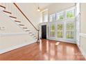 Bright living room featuring hardwood floors, a staircase, plantation shutters, and a front door at 1161 Stuarts Landing Dr, Cramerton, NC 28032