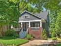 Two-story home featuring a cozy front porch with classic white columns and brick accents surrounded by lush greenery at 2121 Club Rd, Charlotte, NC 28205