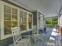 Relaxing front porch with two rocking chairs, gray floors, and views of the lush green surroundings at 2121 Club Rd, Charlotte, NC 28205