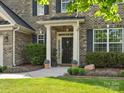 Elegant front entrance with black door, white pillars, and landscaped garden at 2467 Chatham Dr, Indian Land, SC 29707