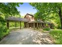 Brick home with a portico and long covered porch, surrounded by lush trees, offering a serene setting at 332 York Spann Rd, Hamptonville, NC 27020