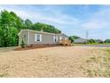 Exterior side view of single story home with front porch, gravel driveway and treed backyard at 445 Davis Rd, Shelby, NC 28152