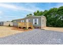 View of the home with charming porch and landscaping, set on a gravel lot at 445 Davis Rd, Shelby, NC 28152