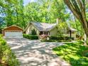 Lovely home featuring a detached garage, ample parking, lush landscaping, and mature trees at 5719 Doncaster Dr, Charlotte, NC 28211
