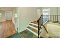 Unique staircase with hardwood steps, decorative iron railing and stone floor detail at 5719 Doncaster Dr, Charlotte, NC 28211