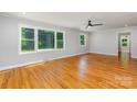 Spacious living room featuring gleaming hardwood floors, ample natural light from large windows, and a modern ceiling fan at 6007 Charing Pl, Charlotte, NC 28211