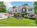 Beautiful home with lush green lawn, mature trees, and a convenient PODS moving container in the driveway at 8056 Stevens Mill Rd, Matthews, NC 28104