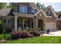 Close-up of a brick home featuring a stone archway, well-manicured landscaping, and a charming front porch at 938 Rock Forest Way, Fort Mill, SC 29707