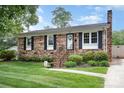 Charming brick home with mature landscaping, black shutters and inviting front porch at 1005 N Main St, Mount Holly, NC 28120