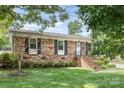 Charming brick home with mature landscaping, black shutters and inviting front porch at 1005 N Main St, Mount Holly, NC 28120
