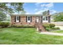 Charming brick home with mature landscaping, black shutters and inviting front porch at 1005 N Main St, Mount Holly, NC 28120