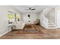 Bright living room with wood flooring, a ceiling fan, and a staircase, creating a cozy atmosphere at 12536 Hennigan Place Ln, Charlotte, NC 28214