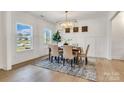 Elegant dining room with wainscoting, wood floors, stylish chandelier, and a view of the outdoors at 1500 Nectar Way # 32, Kannapolis, NC 28083