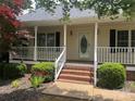 Inviting front porch with brick steps and white railing, framed by green bushes and flowerbeds at 165 Graceland Pl, Salisbury, NC 28146