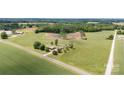 An aerial view of a property with a brick home surrounded by lush greenery, fields, and a quiet country road at 1870 Sloan Rd, Mt Ulla, NC 28125