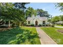 Charming white Tudor-style home with a well-manicured lawn on a sunny day at 2033 Charlotte Dr, Charlotte, NC 28203