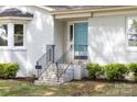 Close-up of a stylish white brick house featuring a striking bright blue front door and black railings at 22330 Torrence Chapel Rd, Cornelius, NC 28031