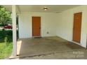 Neutral painted carport with concrete floor, an exterior door and space for parking vehicles at 2322 Hedgewood Cir, Gastonia, NC 28052