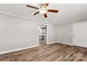 Bright living room with wood-look floors, crown molding, neutral paint, ceiling fan, and open doorway to the kitchen at 2322 Hedgewood Cir, Gastonia, NC 28052