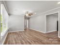 Spacious living room featuring wood-look floors, large windows, crown molding, neutral paint, and ceiling fan at 2322 Hedgewood Cir, Gastonia, NC 28052