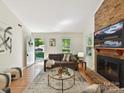 Cozy living room with a brick fireplace, hardwood floors, and view of the front yard at 2401 Birnen Dr, Charlotte, NC 28210