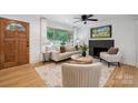 Bright living room with hardwood floors, large windows, stylish furniture, and a cozy fireplace at 4021 Paisley Pl, Charlotte, NC 28208