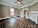 Inviting living room with dark wood floors, a ceiling fan, and an ornate fireplace. Open doorways lead to adjoining rooms at 419 S Spencer Ave, Spencer, NC 28159