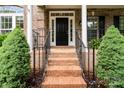 Inviting front porch with brick steps, black railings, and lush greenery adding curb appeal at 6729 Garden Hill Dr, Huntersville, NC 28078
