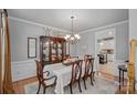 Elegant dining room with hardwood floors, chandelier, wainscoting, and a glimpse into the kitchen at 1400 Coachman Dr, Waxhaw, NC 28173