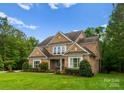 Elegant brick home featuring a well-maintained lawn and mature trees, showcasing its curb appeal at 1410 Smoketree Ct, Waxhaw, NC 28173