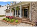 Welcoming front porch with white columns, black shutters, and colorful landscaping at 14849 Middlesborough Dr, Matthews, NC 28104
