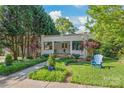 Inviting home exterior with manicured lawn and landscaping, plus a cozy blue Adirondack chair at 1822 Hall Ave, Charlotte, NC 28205