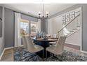 Elegant dining area features a modern chandelier, neutral decor, and a staircase in the background at 2010 Puddle Pond Rd, Indian Trail, NC 28079