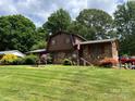 View of a brick home with neatly maintained lawn, mature plants, and a decorative water fountain at 204 Aspen Dr, Gastonia, NC 28052
