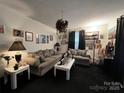 Inviting living room featuring neutral-toned sofas, dark carpet, and an array of personal decor and art at 204 Aspen Dr, Gastonia, NC 28052