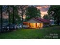 Charming lakefront home with a red roof, inviting screened porch, and gazebo at sunset at 4599 B & C Dr, Catawba, NC 28609