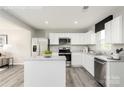 Modern kitchen features stainless steel appliances, white cabinets, granite countertops, and a central island for meal preparation at 5782 Knox Ln, Kannapolis, NC 28081