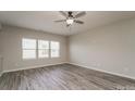 Bright living room with gray wood floors, a ceiling fan, and natural light from the windows at 9127 Colwick Hill Ln, Charlotte, NC 28215