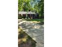 Brick home with walkway, white rocking chairs, driveway, and mature landscaping at 10624 Wood Meadow Dr, Charlotte, NC 28227