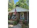 Welcoming covered front porch with chairs and brick facade with an American flag at 10624 Wood Meadow Dr, Charlotte, NC 28227