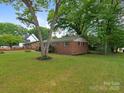 Exterior view of a single story brick house, showcasing the spacious yard with mature trees at 1100 Clawson Ct, Charlotte, NC 28209