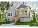 Inviting one-story home featuring gray siding and a charming front porch with wooden stairs and railings at 1101 Kenly St, Salisbury, NC 28144