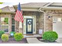 Home's inviting front porch, showcasing a brick facade, decorative wreath, and well-maintained landscaping at 14113 Highland Meadow Rd, Charlotte, NC 28273