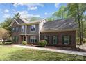 Traditional brick and siding house with green shutters, complemented by a lush lawn and mature trees at 15324 Yarmouth Rd, Mint Hill, NC 28227