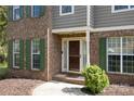Close-up of a classic brick home's entrance, accented by green shutters and a neatly landscaped garden at 15324 Yarmouth Rd, Mint Hill, NC 28227