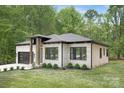 Beautifully landscaped home with white brick exterior, black framed windows, and a black garage door at 1534 Easy St, Belmont, NC 28012