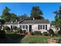 Charming, whitewashed brick home with manicured landscaping, black shutters, and a cozy front porch at 1904 Lynnwood Dr, Charlotte, NC 28209