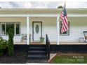 Inviting front porch with black brick base, rocking chairs, and a U.S. flag at 2054 Hickory Hills Dr, Denver, NC 28037