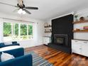 Cozy living room boasts a brick fireplace, floating shelves, and a large window with natural light at 2054 Hickory Hills Dr, Denver, NC 28037